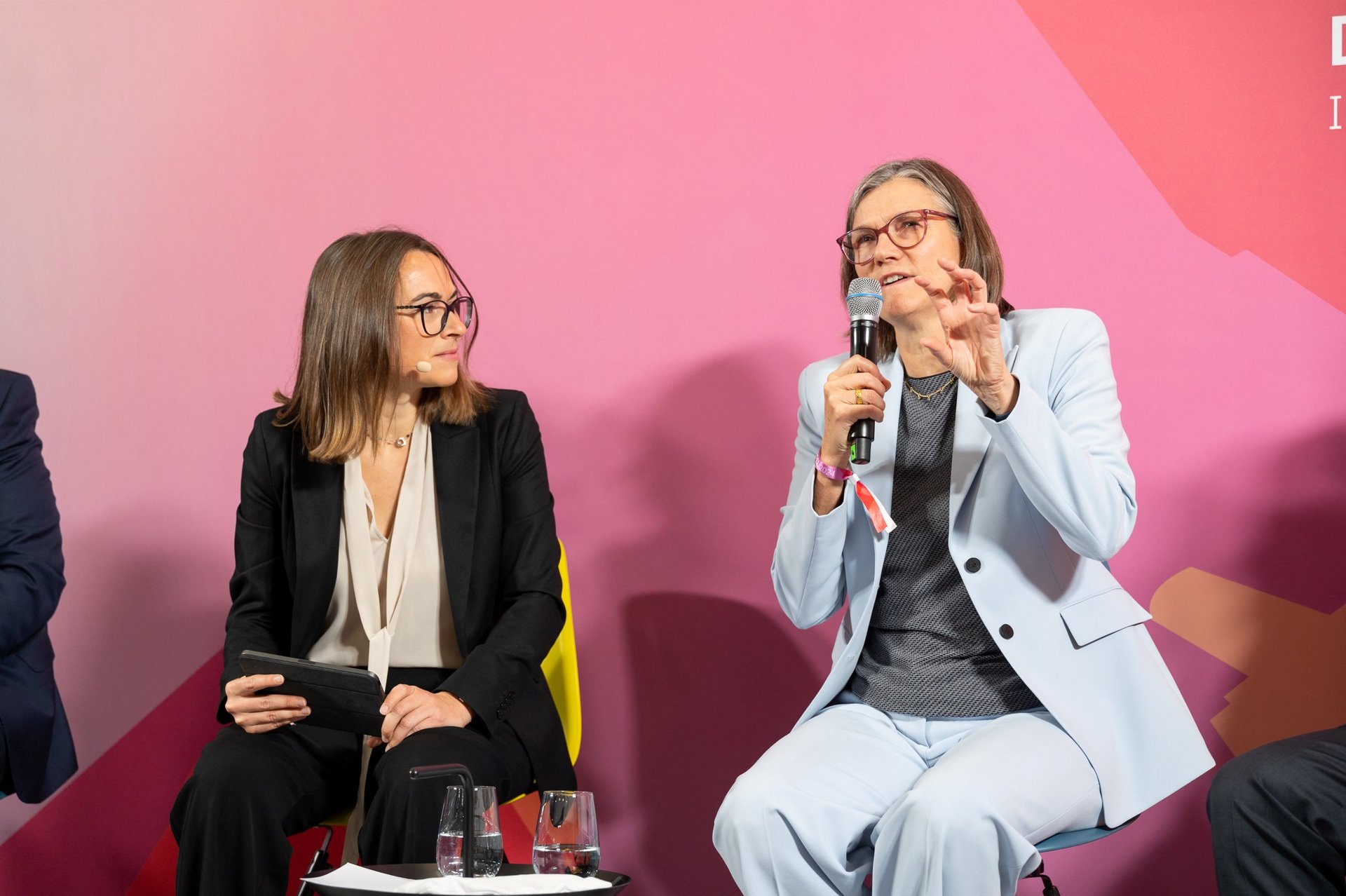 Christiane Benner, hält ein Mikrofon in der Hand und spricht. Links neben ihr sitzt die Moderatorin der Diskussion, Larissa Holzki.